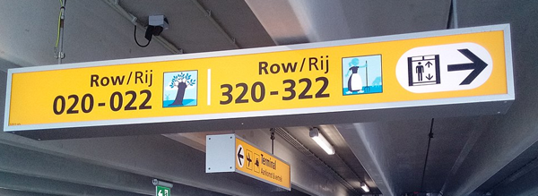 Figure 4. An example of a sign that supports multiple functions at once. This sign is an identification sign (you are at Row 020-022) and a directional sign (elevators are to the right). Photo by Donald Trung Quoc Don, 2019 (CC-BY-SA). bit.ly/3aqe12K.