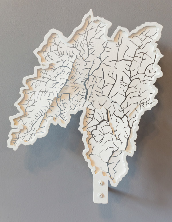 A sculpture of another watershed, similar to the first. A white background into which have been cut the shapes of streams. Photo by Charles P. Rader.