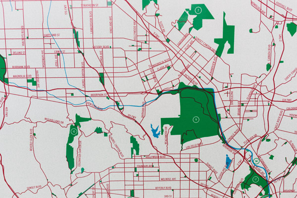 A detail of a map showing a red road network on a white background. Green polygons and a blue river network can also be seen. Photo by Charles P. Rader.