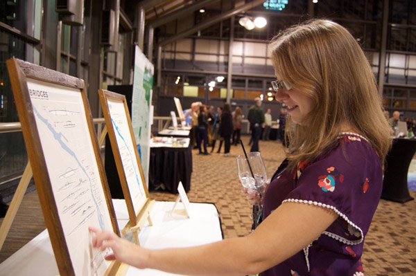 A person looking at a pair of maps on stands on a table. This person is touching one of the maps. Photo by Dylan Moriarty.