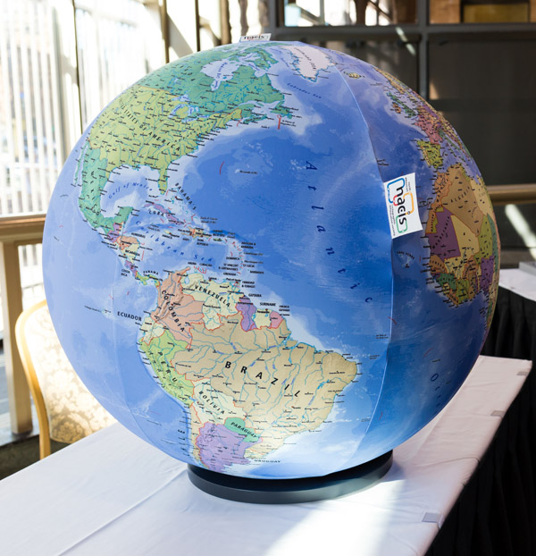 A large political globe, with blue water and countries in various colors. Each country is labeled, as are many cities. The globe is sitting on a small stand atop a table. Photo by Charles P. Rader.
