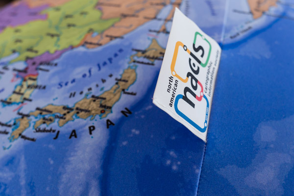 A close-in detail of the globe, showing Japan, as well as a small tag sticking out of the side of the globe, sewn into a seam. The tag shows the logo of the North American Cartographic Information Society. Photo by Charles P. Rader.