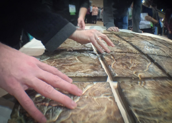 A close-in photo of a person's hands touching some of the tiles. Photo by Matt Dooley.